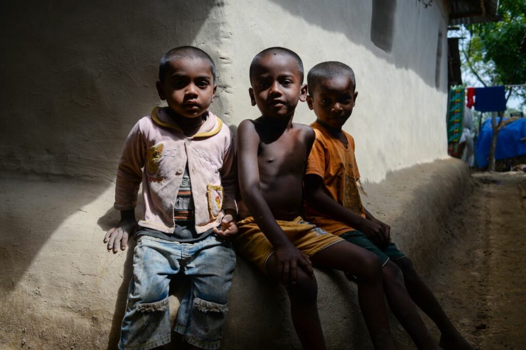 Three young boys sitting against a rustic wall, showcasing natural light and candid expressions.
